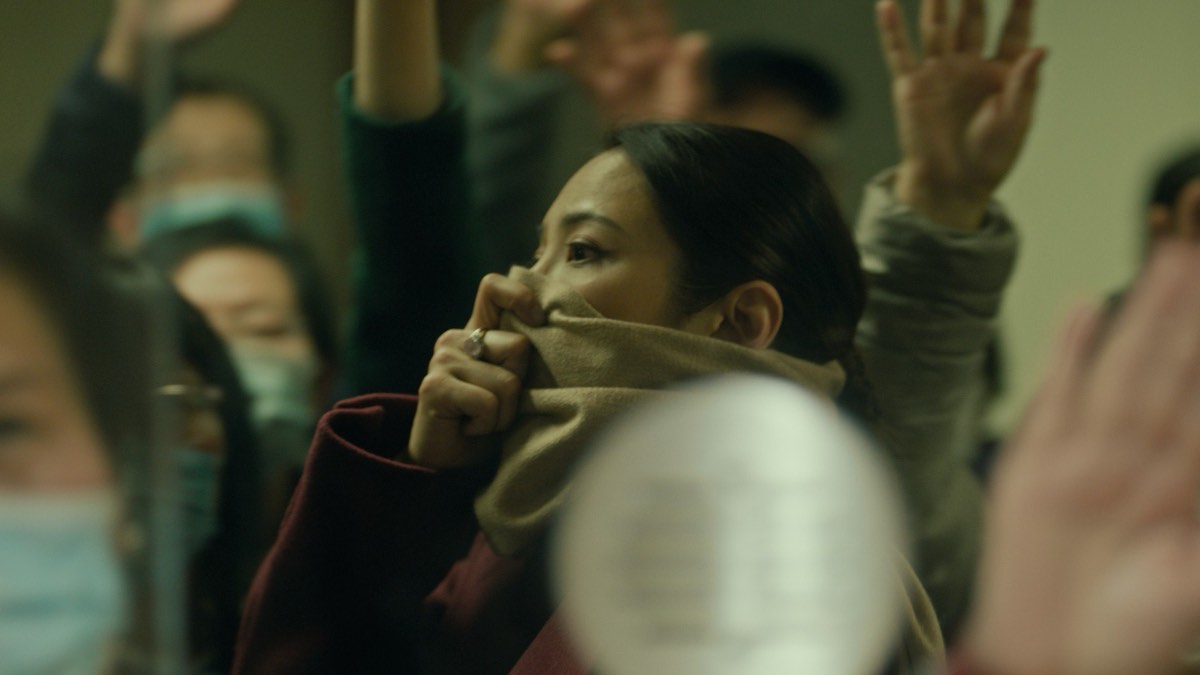 《超限戰》劇照：一名女子以圍巾掩住口鼻，身處舉手呼喊的人群之中
